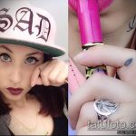 Фотография татуировки на пальце руки: маленькая птичка и капля слезы. Чёрно-белое изображение, девушка в кепке.