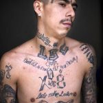 Фотография татуировки на теле мужчины: множество татуировок, включая надписи, символы и рисунки. Чёрно-белое изображение.