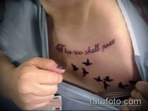 Фото тату: татуировка с изображением летящих птиц и фразы "This too shall pass" на груди.