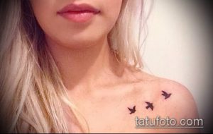 Фото тату нескольких маленьких черных птиц на ключице девушки. Нежный и минималистичный рисунок татуировки.