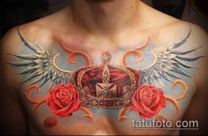 Фото татуировки на груди: корона, окруженная розами и крыльями ангела. Детализированный рисунок в ярких цветах.