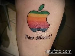 Фото тату яблока Apple в стиле ретро с радужной расцветкой и надписью 'Think different!', выполненное на руке.