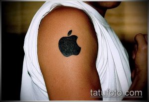 Фото тату логотипа Apple на плече. Черный контурный рисунок татуировки, выполненный в классическом стиле, расположен на плече.