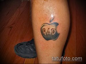 Фото татуировки логотипа Apple с надписью 'RAD' внутри на икре. Черно-серый рисунок татуировки.