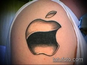 Фото тату логотипа Apple на плече. Черно-серый рисунок татуировки с реалистичной прорисовкой яблока и надкушенного фрагмента.
