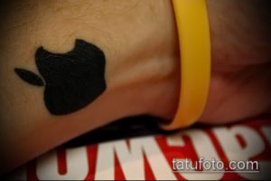 Фото тату логотипа Apple на запястье, выполненного в черном цвете в минималистичном стиле.