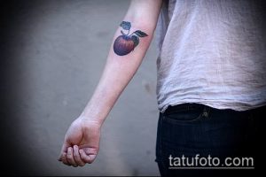 Татуировка на предплечье с изображением красного яблока и зеленого листа. Выполнена в классическом стиле с четкими контурами и насыщенными цветами.