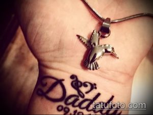 Фото татуировки на запястье с надписью 'Daddy' и изображением колибри. Черно-белый рисунок, символизирующий любовь и память об отце.