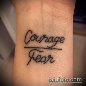 Фото тату с надписью 'Courage over Fear' черным цветом, выполненной на запястье. Простой, но вдохновляющий рисунок татуировки.