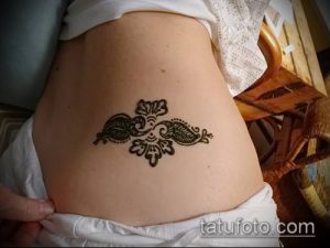 Фотография изящной татуировки хной на животе, выполненной в традиционном восточном стиле с использованием сложных узоров.
