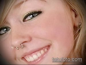 Фотография девушки с пирсингом носа, украшенным двумя серебряными гвоздиками в одной ноздре. Простой и элегантный образ.