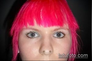 Фотография девушки с яркими розовыми волосами и пирсингом носа с двумя золотыми шариками в одной ноздре. Молодежный и стильный образ.