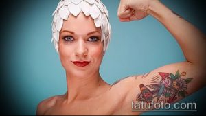 Фото тату: яркая татуировка с изображением летящей ласточки и цветка на плече девушки, выполненная в стиле олдскул.