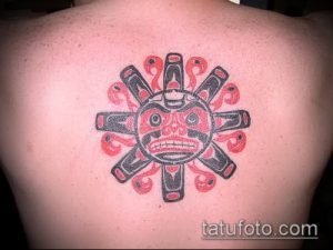 Фото тату на спине: стилизованное солнце в технике Northwest Coast Native Art с черными контурами и красными акцентами.