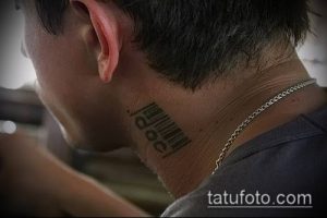 Крупный план татуировки штрих-кода на шее. Черный рисунок татуировки выглядит четко и современно.