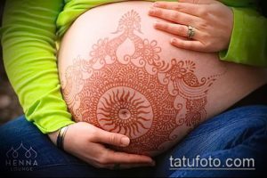 Фото тату хной, узоры на животе, беременность, восточный стиль, коричневые оттенки, детальная проработка, традиционный дизайн.
