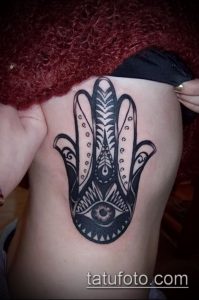 Фото тату Хамса (Рука Фатимы) на боку. Рисунок выполнен в технике blackwork с использованием геометрических узоров и детализации.