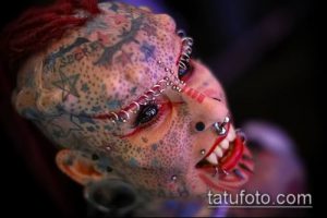 Фотография девушки с экстремальными модификациями тела, включая множество пирсингов, татуировки и шрамирование.