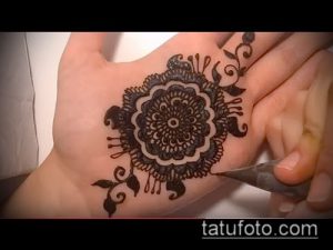 Фото процесса нанесения тату мехенди на руку. Мастер аккуратно наносит узор с помощью специальной пасты.