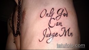 Фото тату надписи 'Only God Can Judge Me' на боку. Черная татуировка, выполненная каллиграфическим шрифтом, подчеркивает индивидуальность.