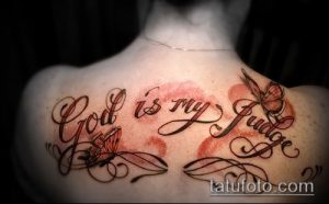 Фото тату надписи 'God is my Judge' с изображением бабочек на спине. Яркий и красочный рисунок татуировки.