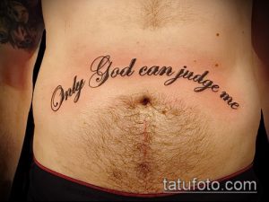 Фото татуировки с надписью 'Only God Can Judge Me' на животе человека, выполненной в изящном шрифте.