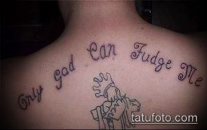 Фото татуировки с надписью 'Only God Can Judge Me' на спине человека, выполненной в простом шрифте с небольшим размытием.