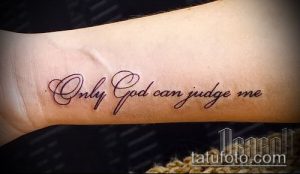 Фото минималистичной татуировки с надписью 'Only God can judge me' красным цветом на запястье.