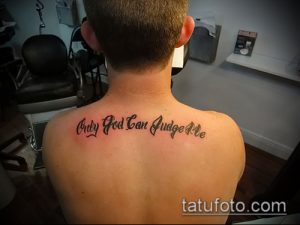 Фото тату надписи 'Only God Can Judge Me' на спине мужчины. Черный шрифт, выполненный в классическом стиле.