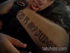 Фото тату надписи 'God Is My Judge' на руке. Коричневый шрифт, выполненный в готическом стиле.