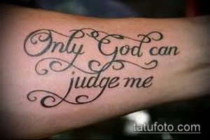 Фото тату надписи 'Only God Can Judge Me' на предплечье. Изящный шрифт с завитушками и детальной проработкой.