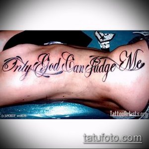 Фото тату надписи 'Only God Can Judge Me' черным цветом, выполненной на боку девушки. Изящный шрифт и плавные линии.