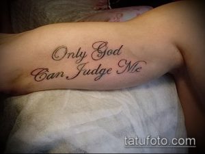 Чёрно-красная татуировка на руке с надписью "Only God Can Judge Me", выполненная каллиграфическим шрифтом.