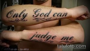 Фотография двух рук с татуировками "Only God Can Judge Me", выполненными каллиграфическим шрифтом с декоративными элементами.