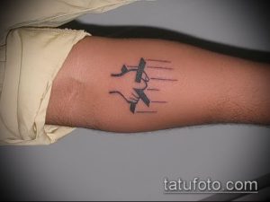 Простая черно-белая татуировка на руке с изображением руки, отпускающей бумажный самолетик. Символизирует свободу и отпускание прошлого.