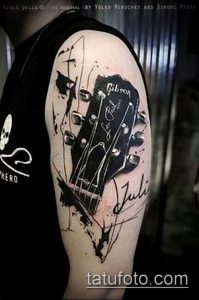 Фото тату гитары Gibson в стиле Trash Polka на плече. Черно-белый рисунок с брызгами краски и надписью 'Julie'.