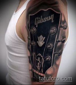 Фотография реалистичной татуировки головы гитары Gibson на плече. Детализированная проработка колков, логотипа и лака.