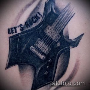 Фото тату электрогитары в стиле реализм с надписью 'Let's Rock!'. Черно-серая татуировка, расположенная на плече.