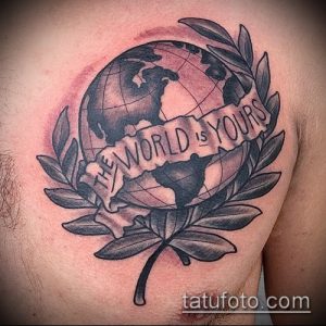 Фото тату глобуса, окруженного лавровым венком, с надписью 'The World is Yours'. Рисунок на груди.