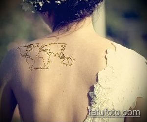 Тонкая, линейная татуировка карты мира на спине девушки, с надписью "wanderlust". Изображение выполнено в нежных тонах.