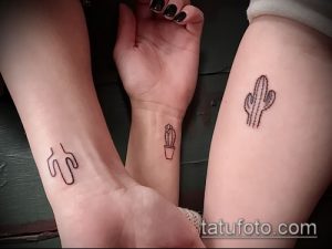 Фото тату: три запястья с минималистичными татуировками кактусов. Один кактус красный, два - черные. Тонкие линии, простой дизайн.