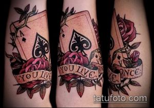 Фото тату на руке: три туза пик, украшенные красными розами и надписью 'YOU LIVE ONCE'. Цветной рисунок татуировки.