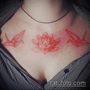 Фото тату: Два красных оригами-журавля и цветок лотоса, выполненные в минималистичном стиле, на груди девушки.