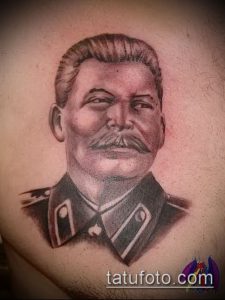 Фото татуировки на плече, изображающей портрет Иосифа Сталина. Рисунок выполнен в реалистичном стиле с использованием теней и бликов.