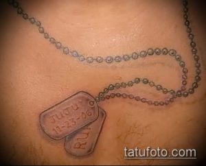 Фото тату: Татуировка в виде двух жетонов с надписями на груди мужчины, выполненная в реалистичном стиле с использованием серых оттенков.