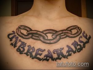 Фото тату надписи 'UNBREAKABLE' с цепью на груди. Рисунок татуировки в стиле леттеринг. Идея для тату для тех, кто ценит силу духа.
