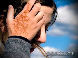 Фото тату мехенди на руке: коричневый цветочный узор, частично закрывающий лицо. Идеально для вдохновения и поиска идей для временных татуировок.