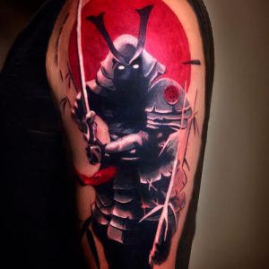 Фото татуировки с изображением самурая в доспехах на фоне красного круга. Яркий и динамичный рисунок в японском стиле.