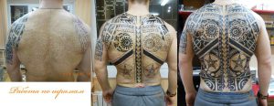 Фото татуировки в стиле маори, покрывающей всю спину. Сложный узор с использованием черных чернил. Вид сзади, этапы работы.