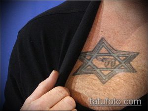 Фото тату: небольшая серая татуировка Звезды Давида на плече мужчины. Минималистичный рисунок татуировки.